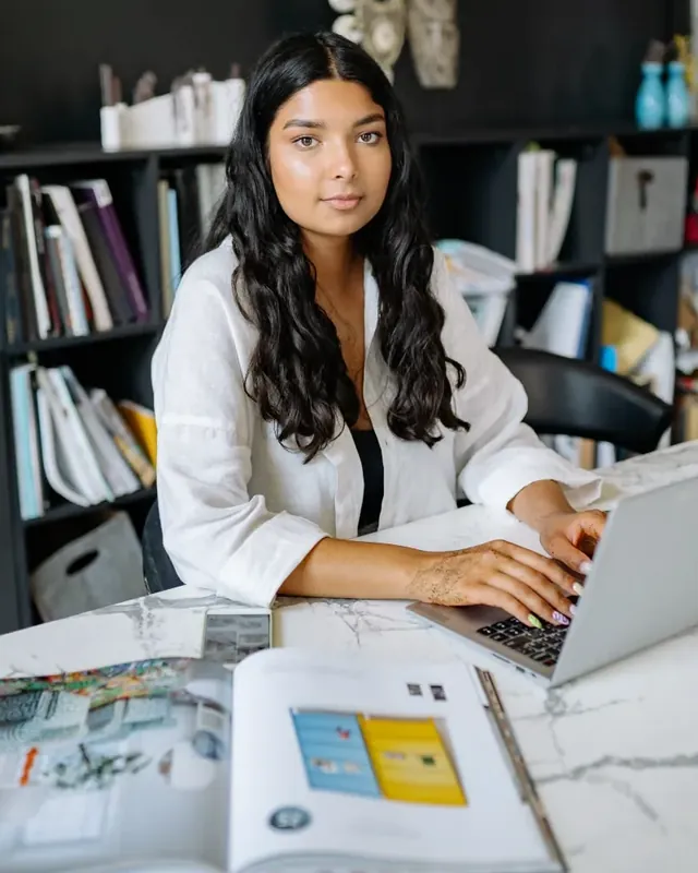 A young woman at her desk, looking confident