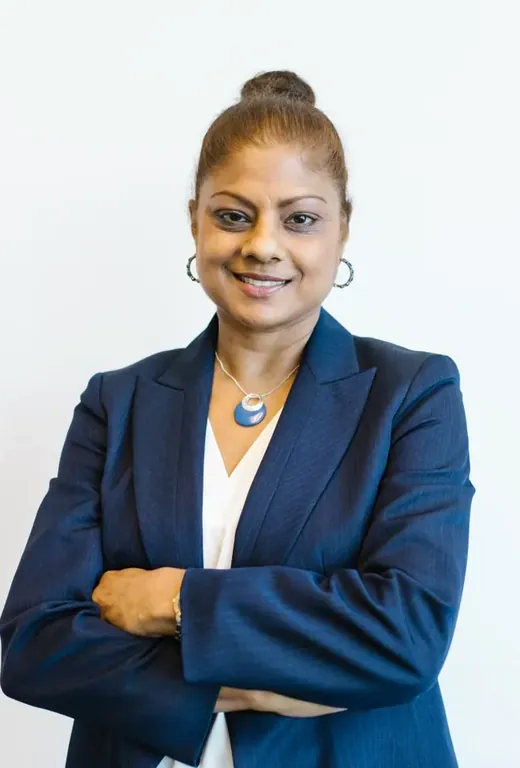 A confident woman in a navy blazer, arms folded